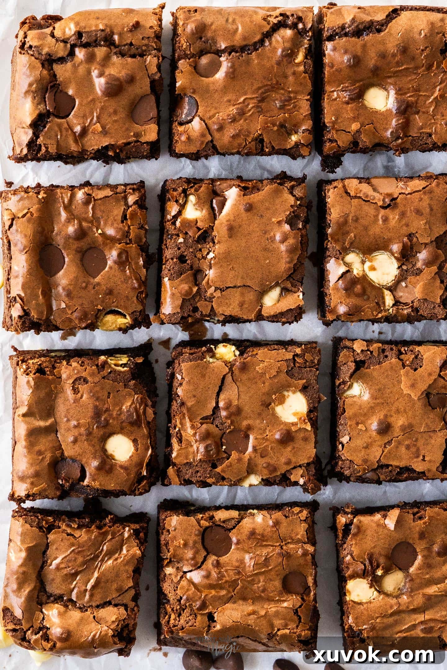 Top down view of 12 perfectly cut triple chocolate brownies, showcasing their rich color and crackly tops.