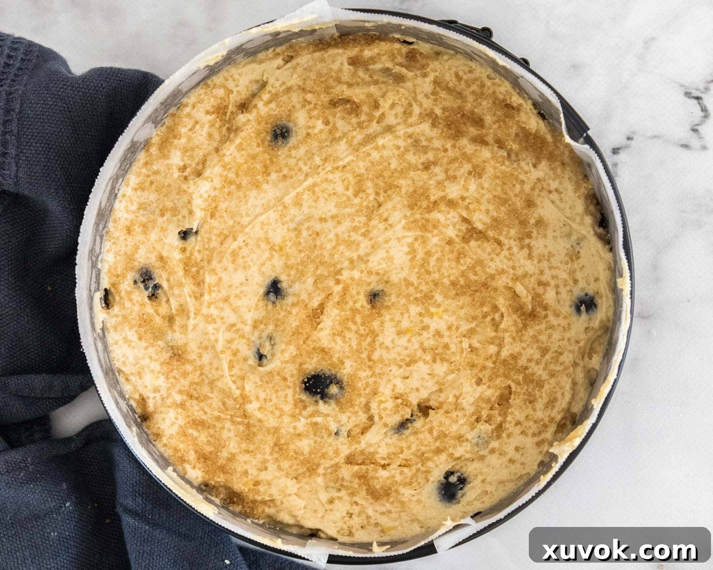The batter in a cake pan with sugar scattered over the time.