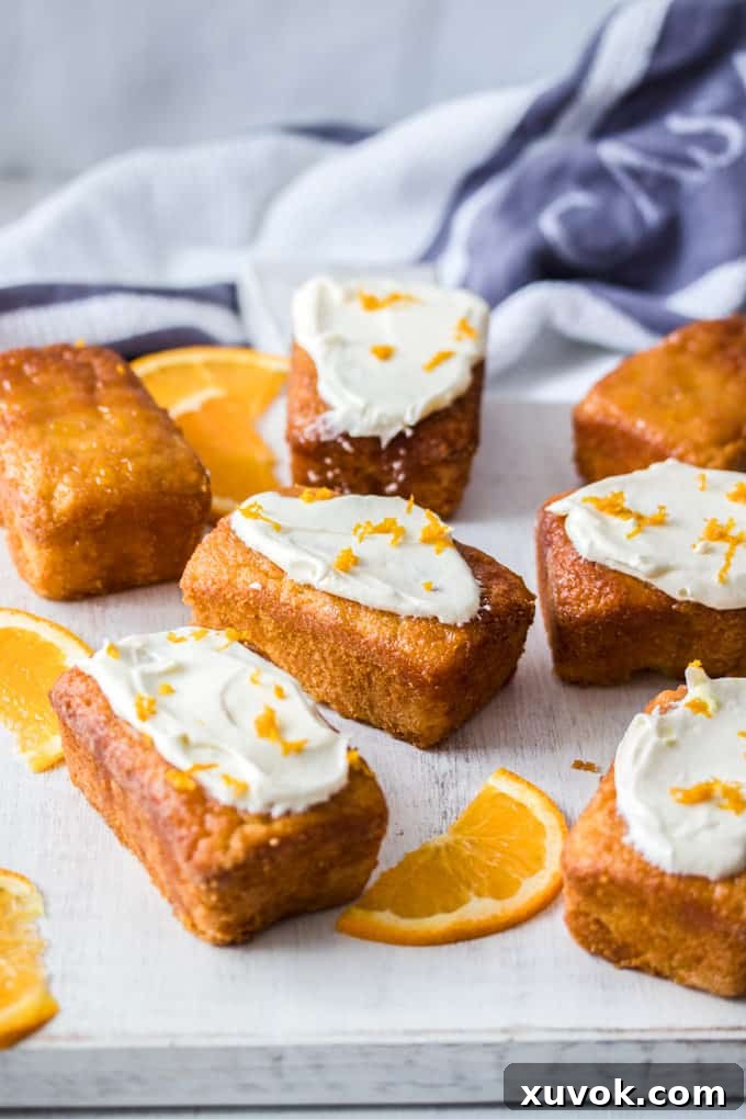 7 Mini Flourless Ginger Orange Cakes on a white board with slices of orange around, beautifully arranged for serving.