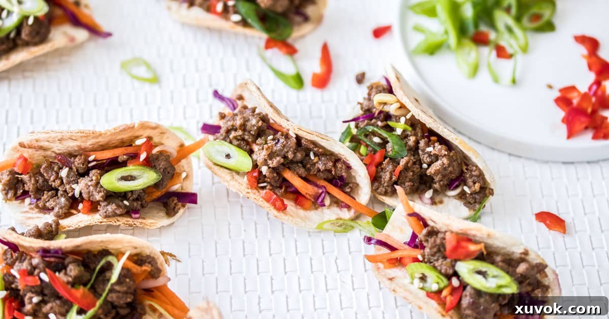 Closeup of 7 mini Korean beef tacos arranged neatly on a white mat, garnished with sesame seeds and spring onions.