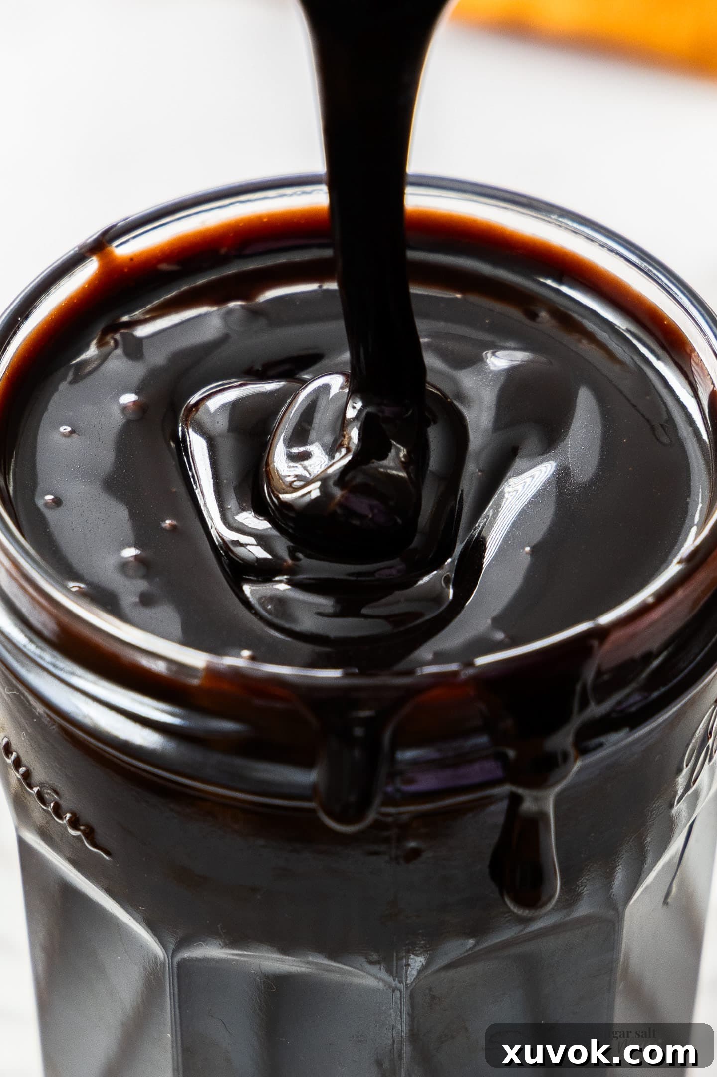 Closeup of a drizzle of the chocolate sauce, showcasing its thick and glossy texture.