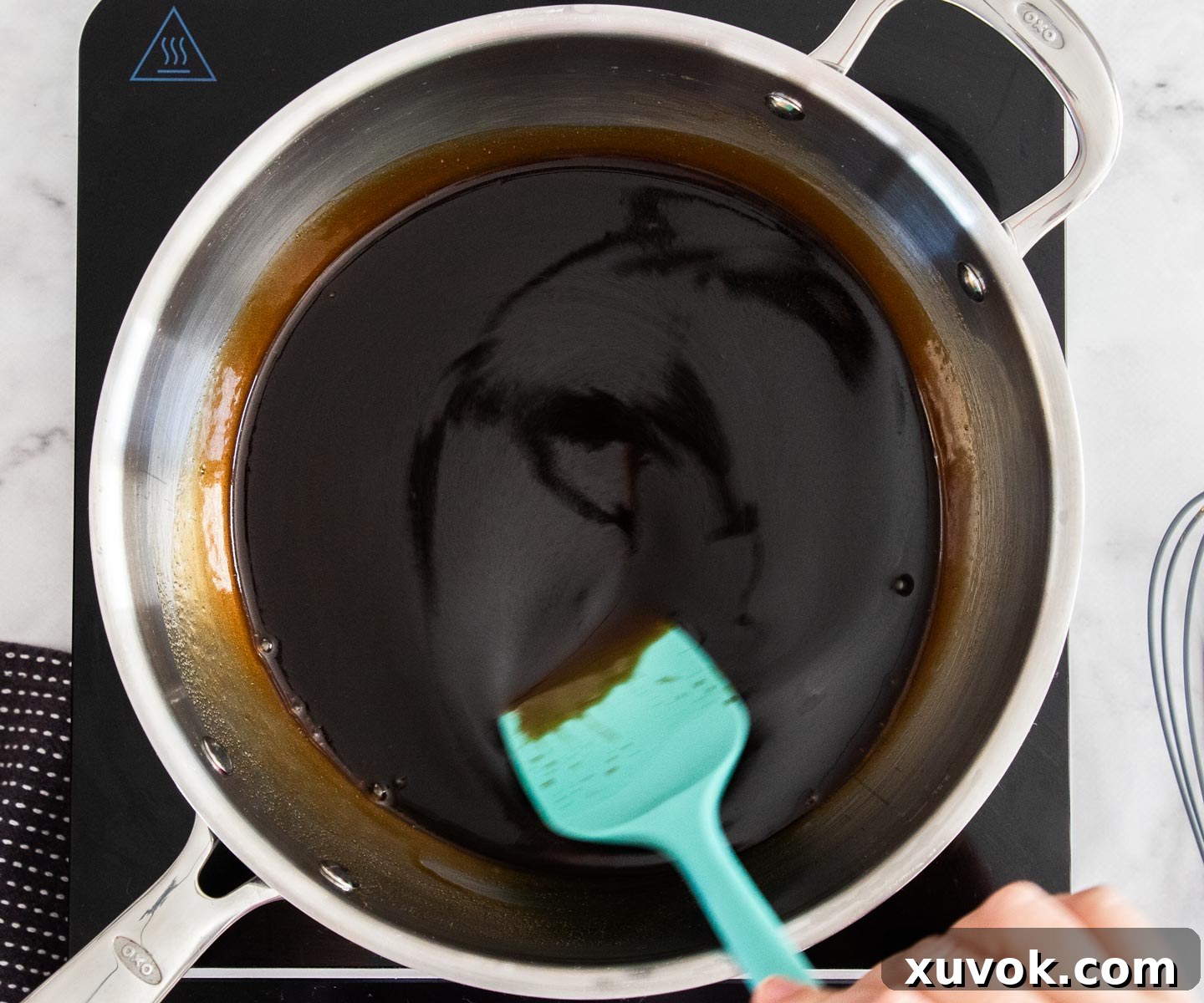 Stirring sugar, butter, and water together in a saucepan on the stove.
