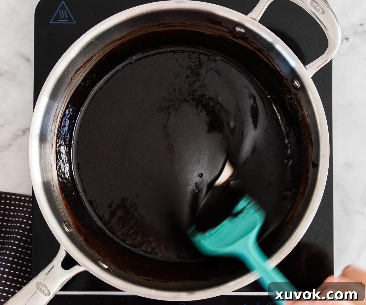 Stirring cocoa powder into the sauce mixture in a saucepan on the stove.