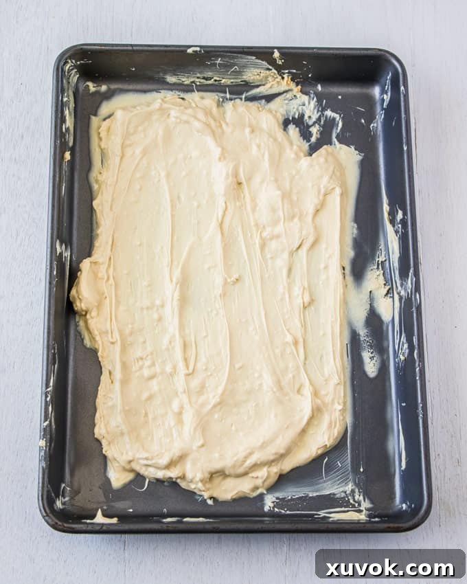 A baking tin covered in melted white chocolate that is being caramelised, showing further browning.