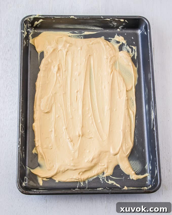 A baking tin covered in melted white chocolate that is being caramelised, showing increasing golden color.