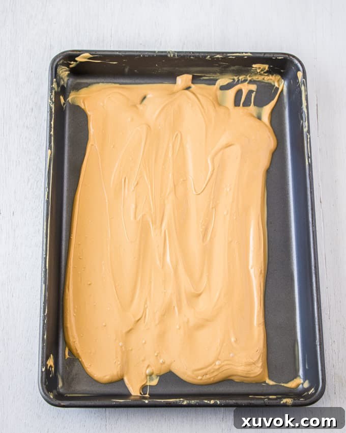 A baking tin covered in caramelised white chocolate, showing its smooth, glossy texture.