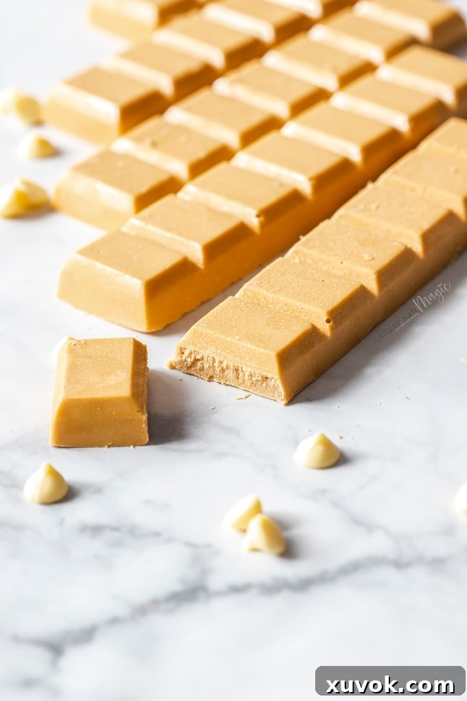 Bars of caramelised white chocolate on a marble surface, surrounded by white chocolate chips.