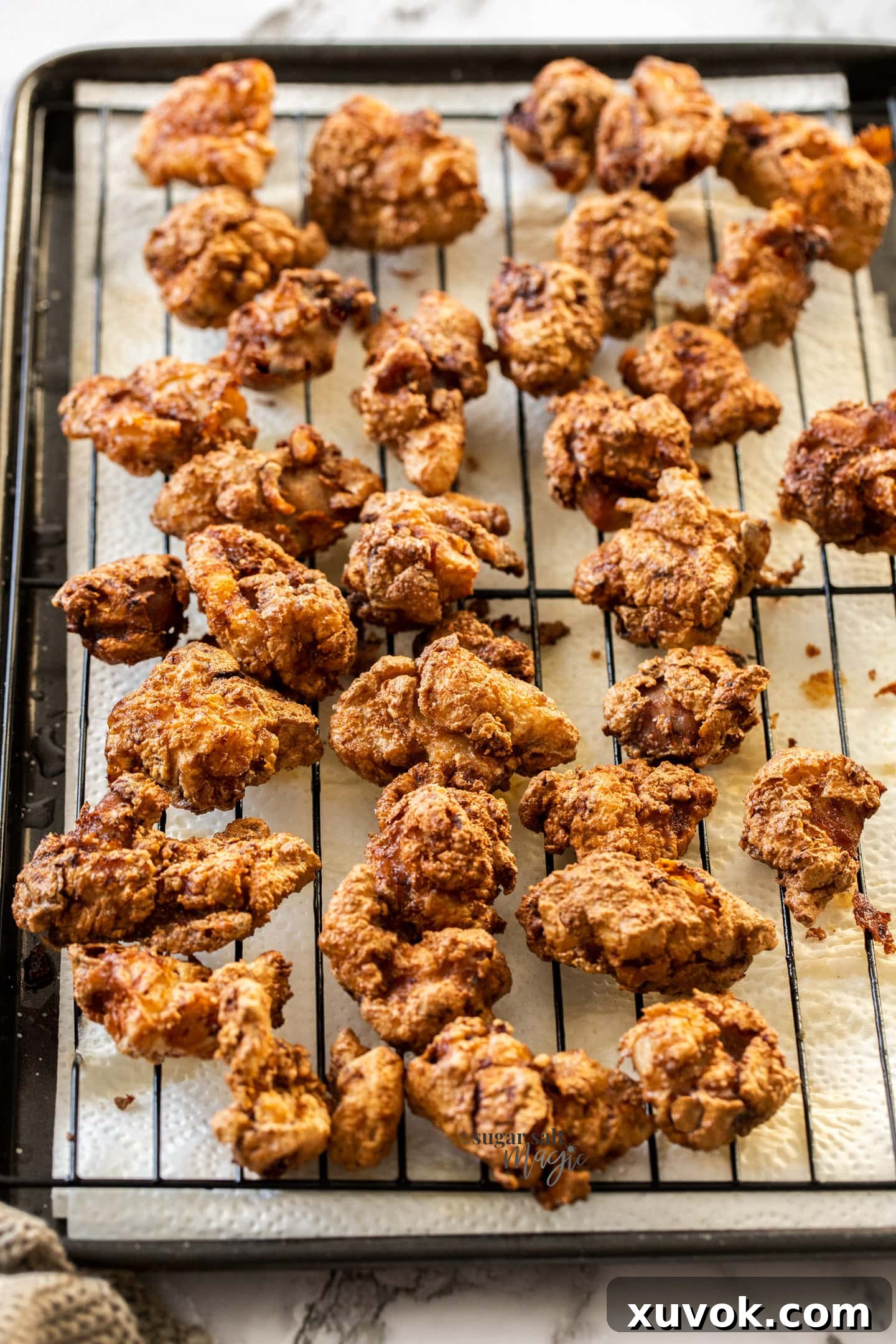 Freshly double-fried Karaage Chicken pieces resting on a wire rack set over paper towels, ready to be served.