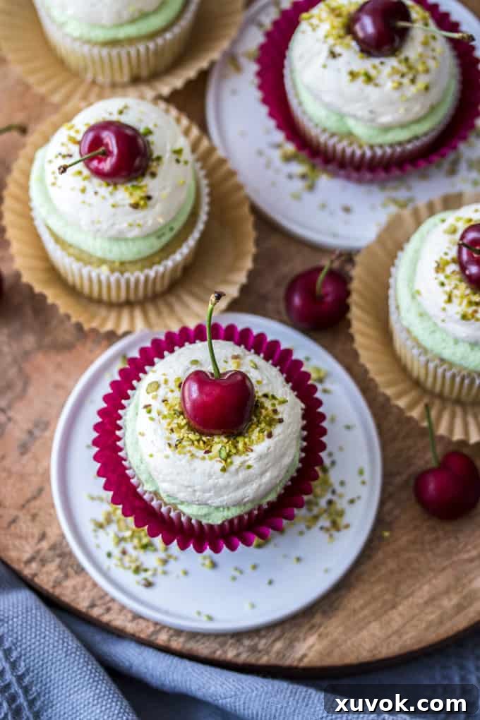 Beautifully decorated Cherry Pistachio Cupcakes with pistachio crumbs and a fresh cherry on top, viewed from above. Perfect for a summer dessert.