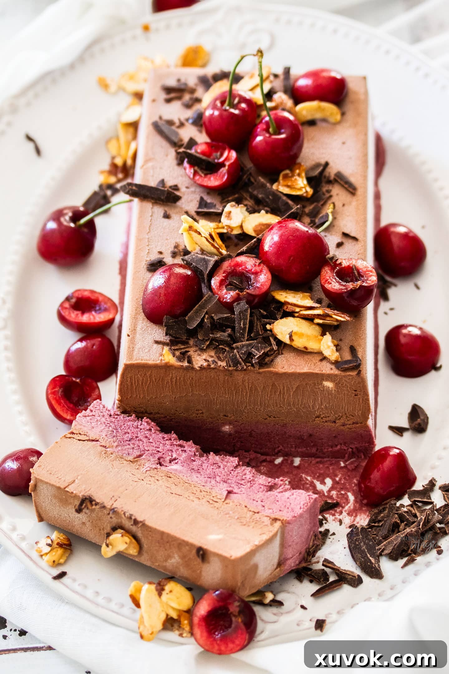 A dual layered frozen parfait topped with cherries, chocolate and almonds.