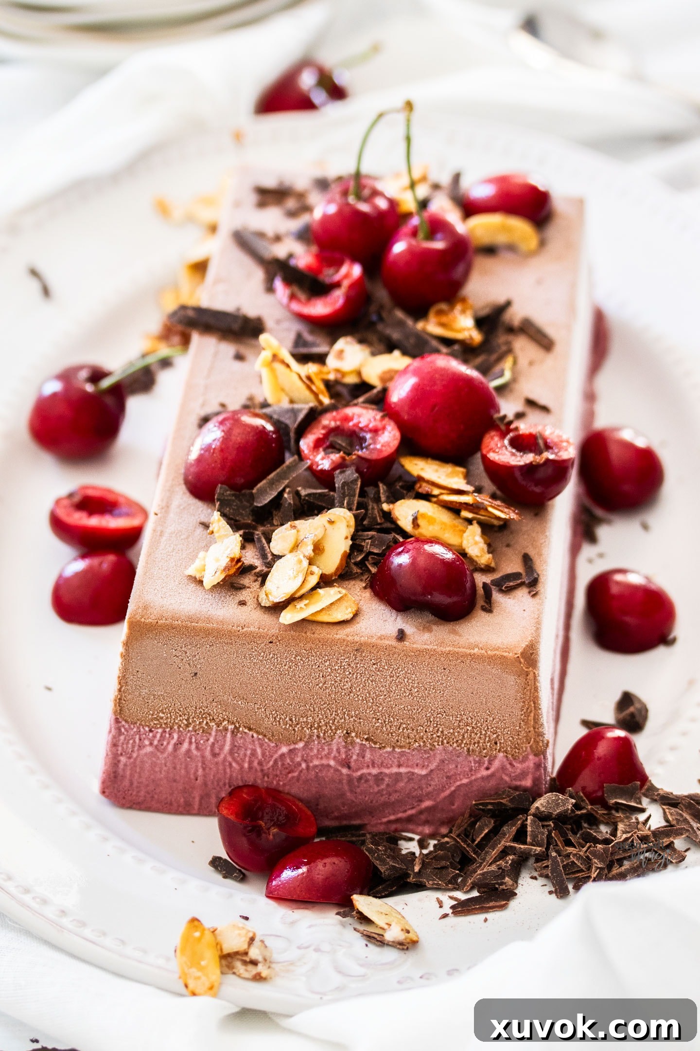 A frozen parfait topped with cherries, chocolate and almonds.