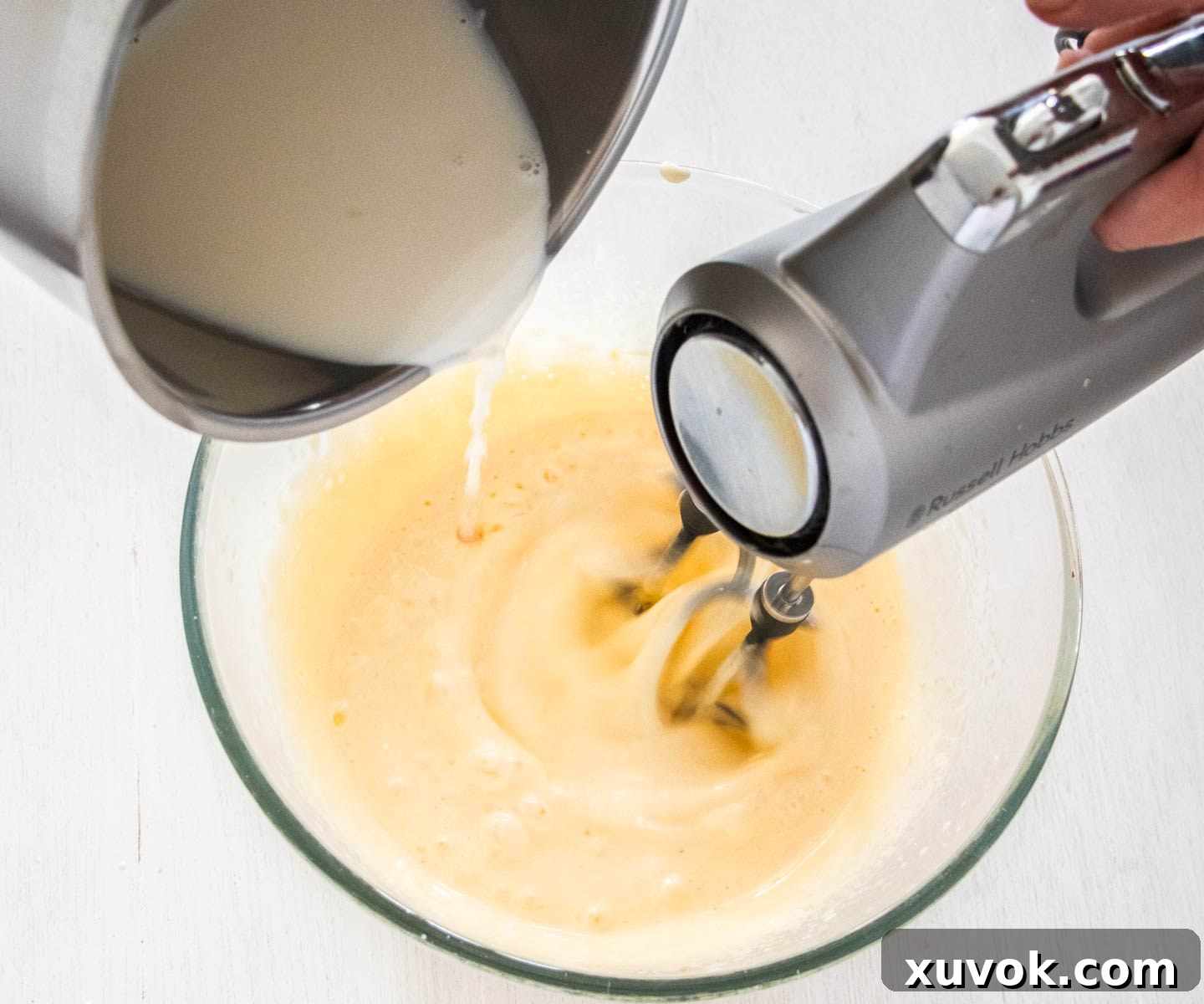 Adding milk to the sugar and eggs.