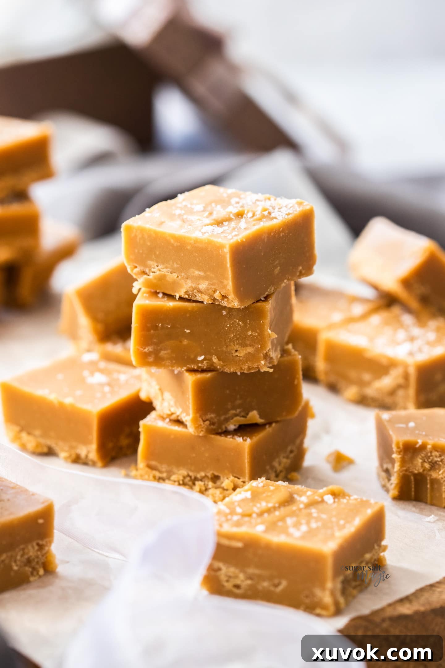 A stack of 4 pieces of caramel fudge, beautifully garnished with sea salt flakes.