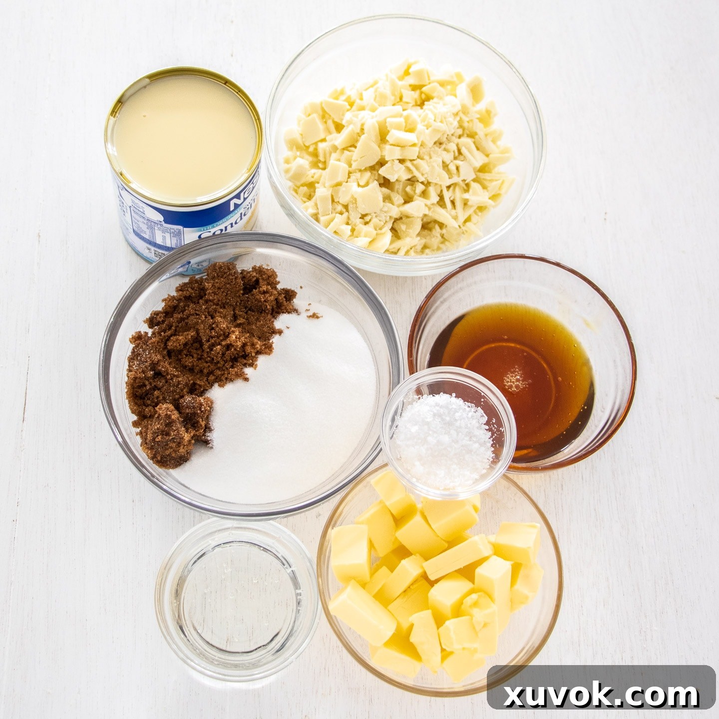 Ingredients for salted caramel fudge laid out on a white wooden bench top.
