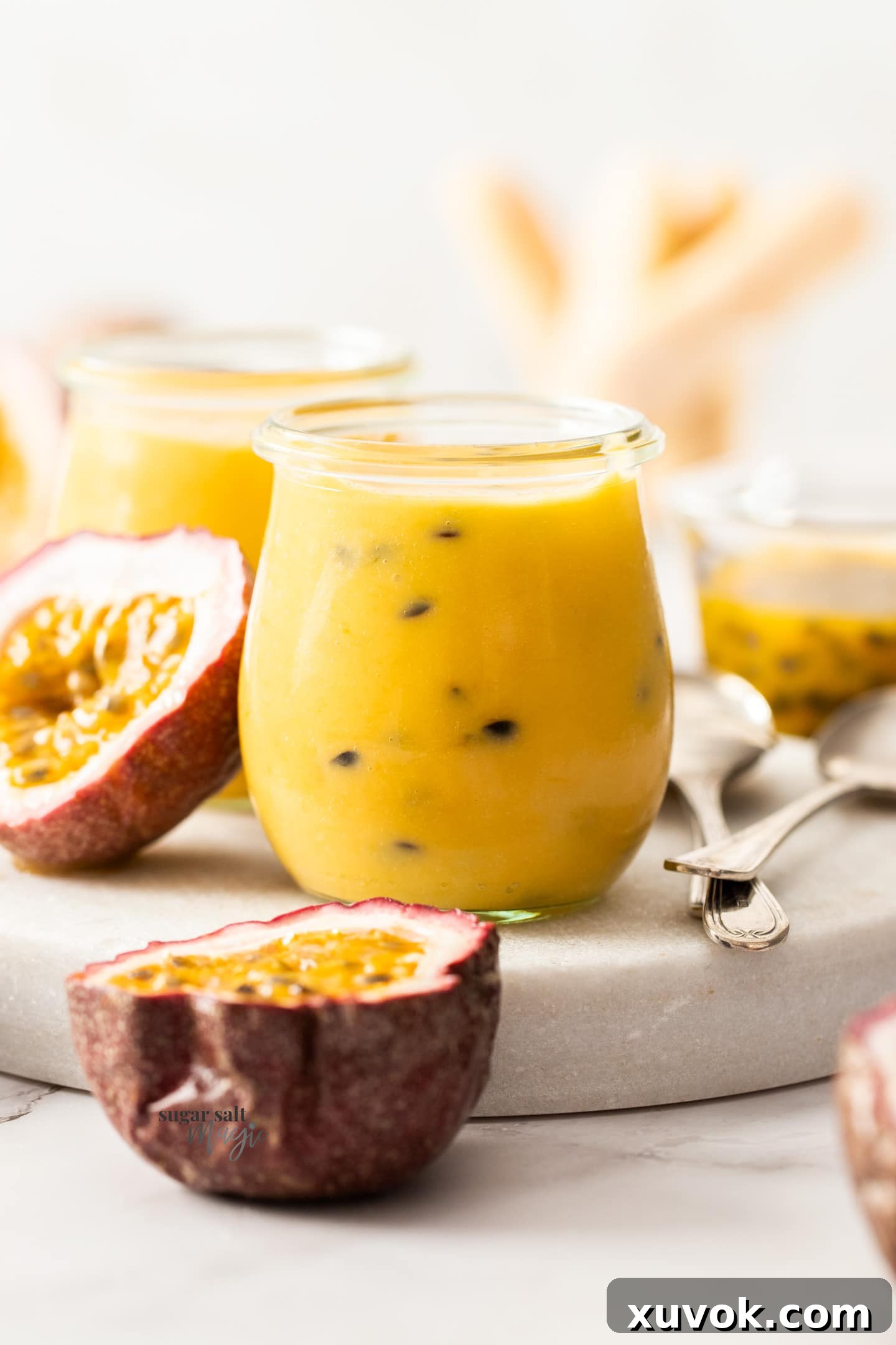 A small, beautifully filled glass jar of homemade passionfruit curd, ready for storing or serving.