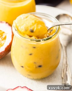A spoon taking passionfruit curd out of a jar.