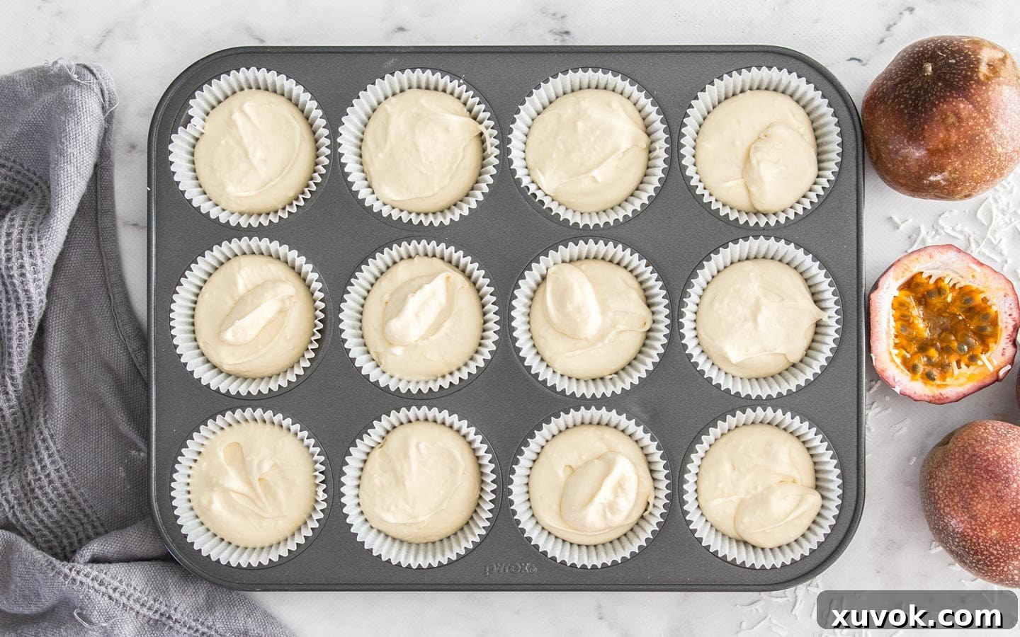 Cupcake batter evenly divided into 12 cupcake liners in a muffin pan, ready for baking.
