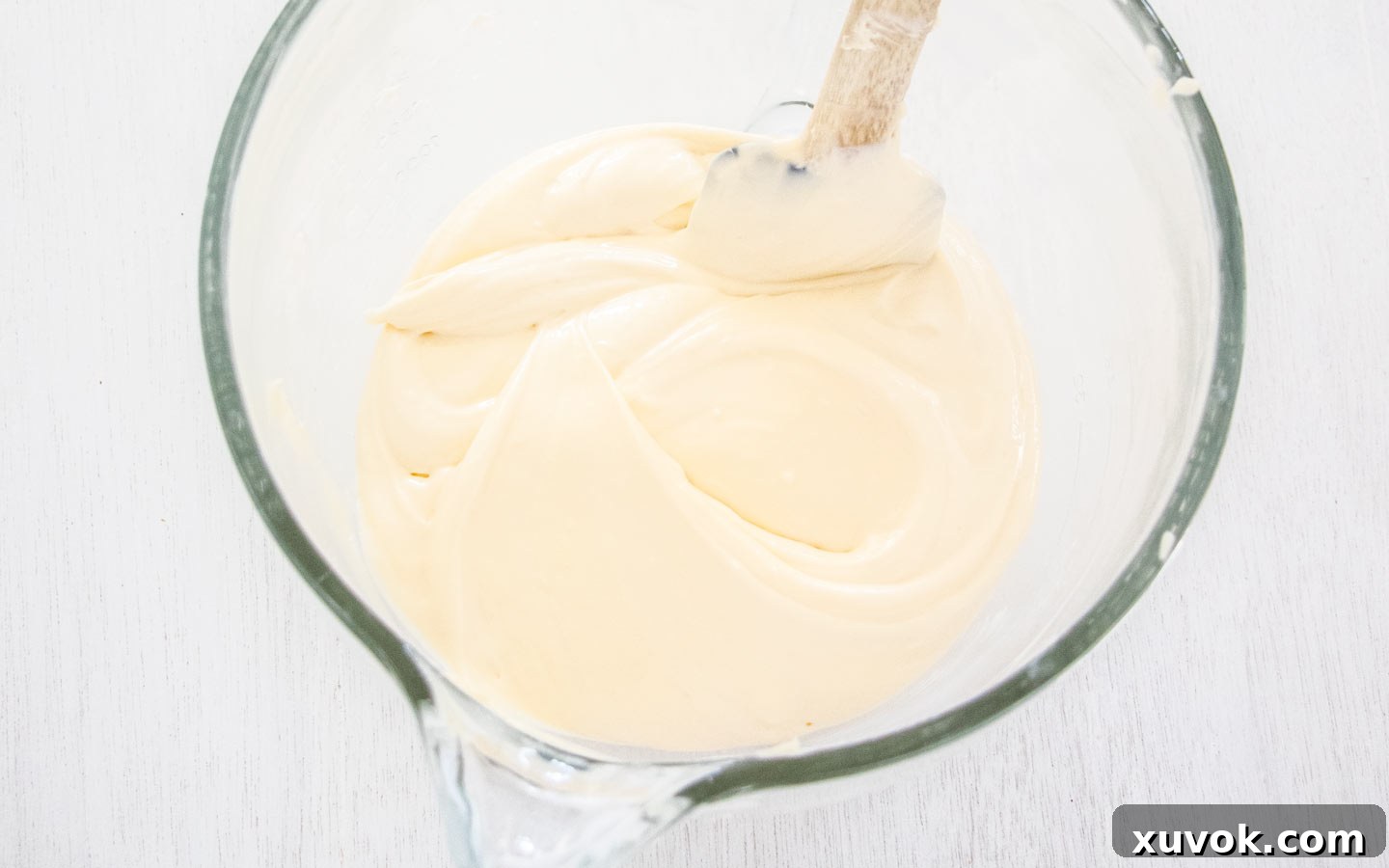 The creamy white cheesecake base, a smooth blend of cream cheese and sugar, in a mixing bowl.