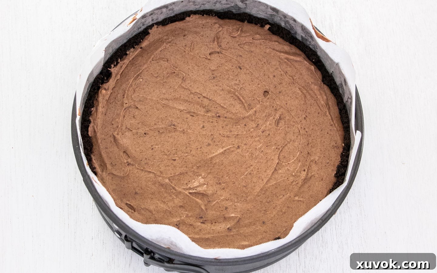 The dark, rich chocolate cheesecake batter poured into the Oreo crust in the springform pan, ready for baking.