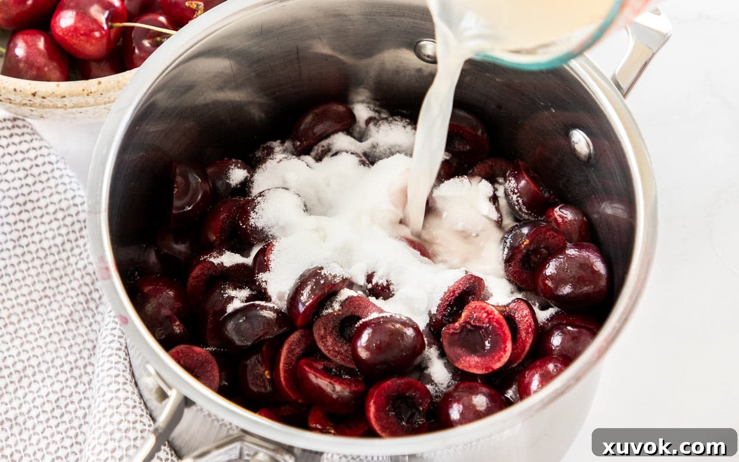 Fresh cherries, water, lemon juice, and sugar combined in a saucepan, beginning to simmer for the cherry sauce.