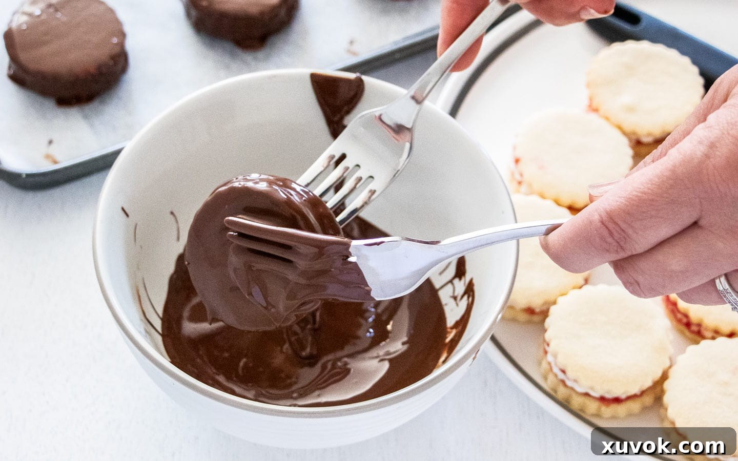 Coating the cookies in melted chocolate, ensuring full coverage.