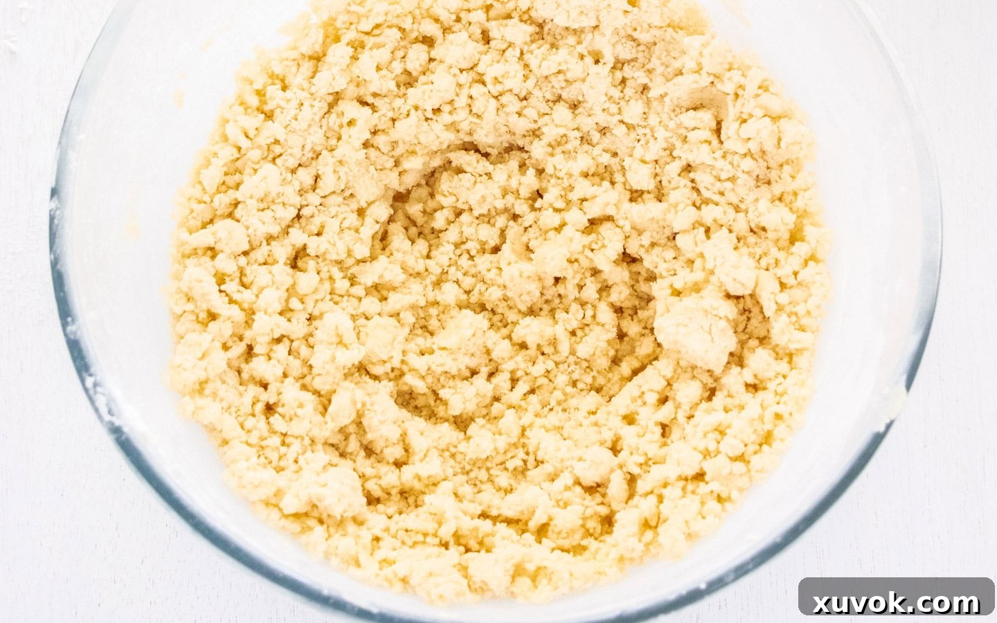 The cookie dough in a bowl, appearing crumbly and ready to be brought together.