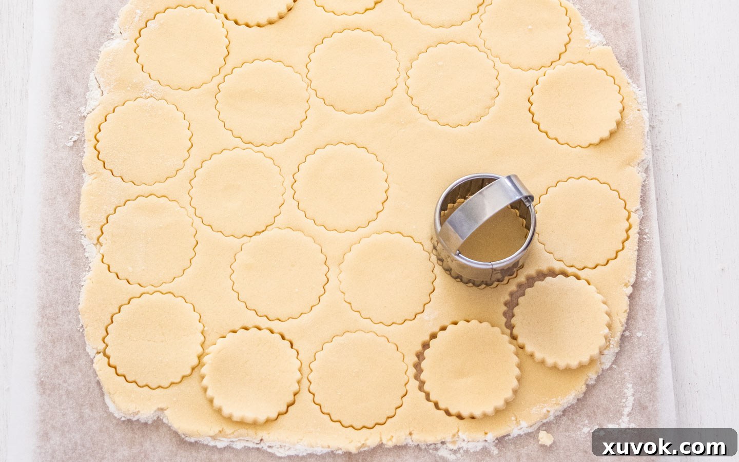 Cutting rounds from the rolled out cookie dough using a fluted cookie cutter.