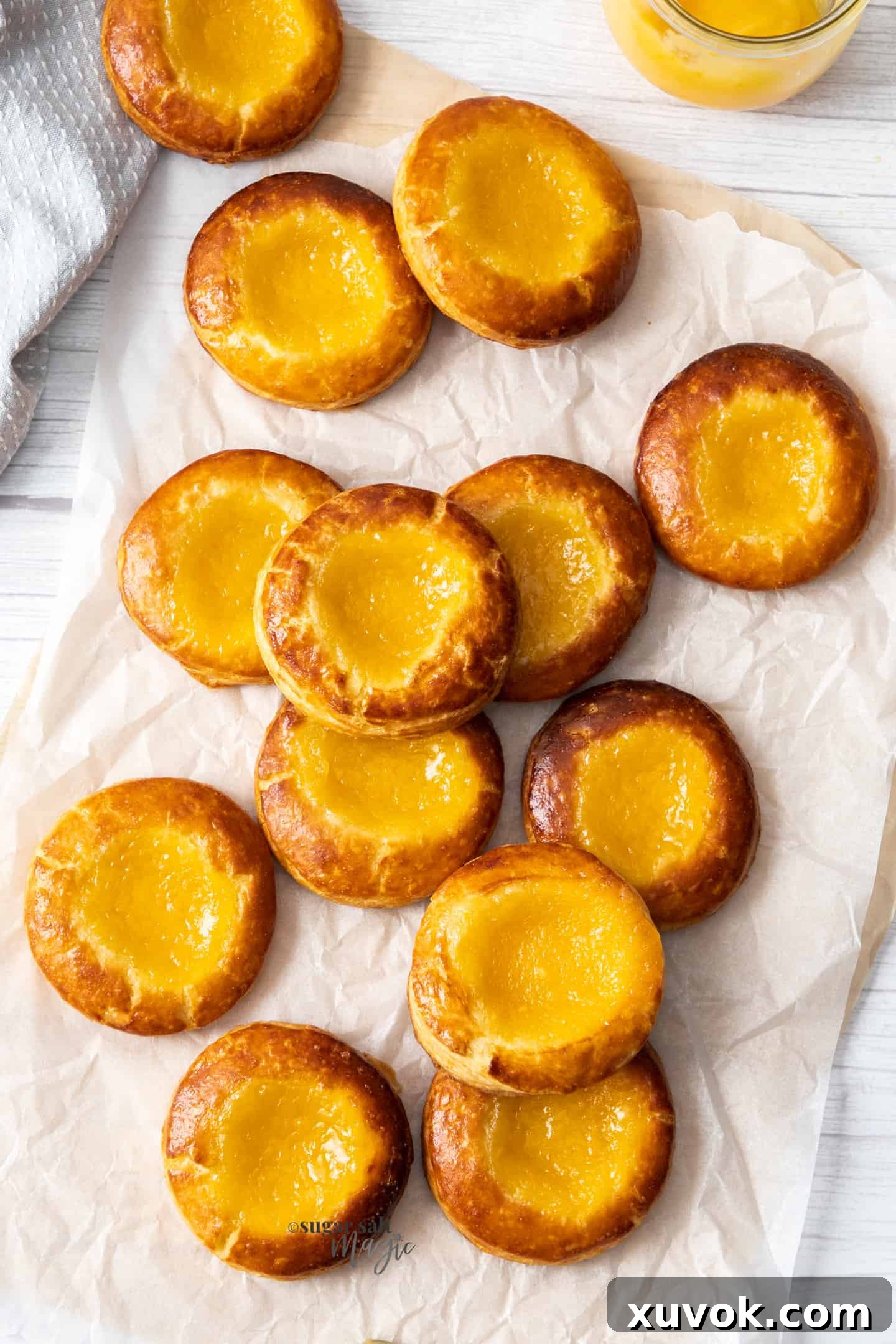 A collection of light, flaky lemon danish pastries on baking paper.