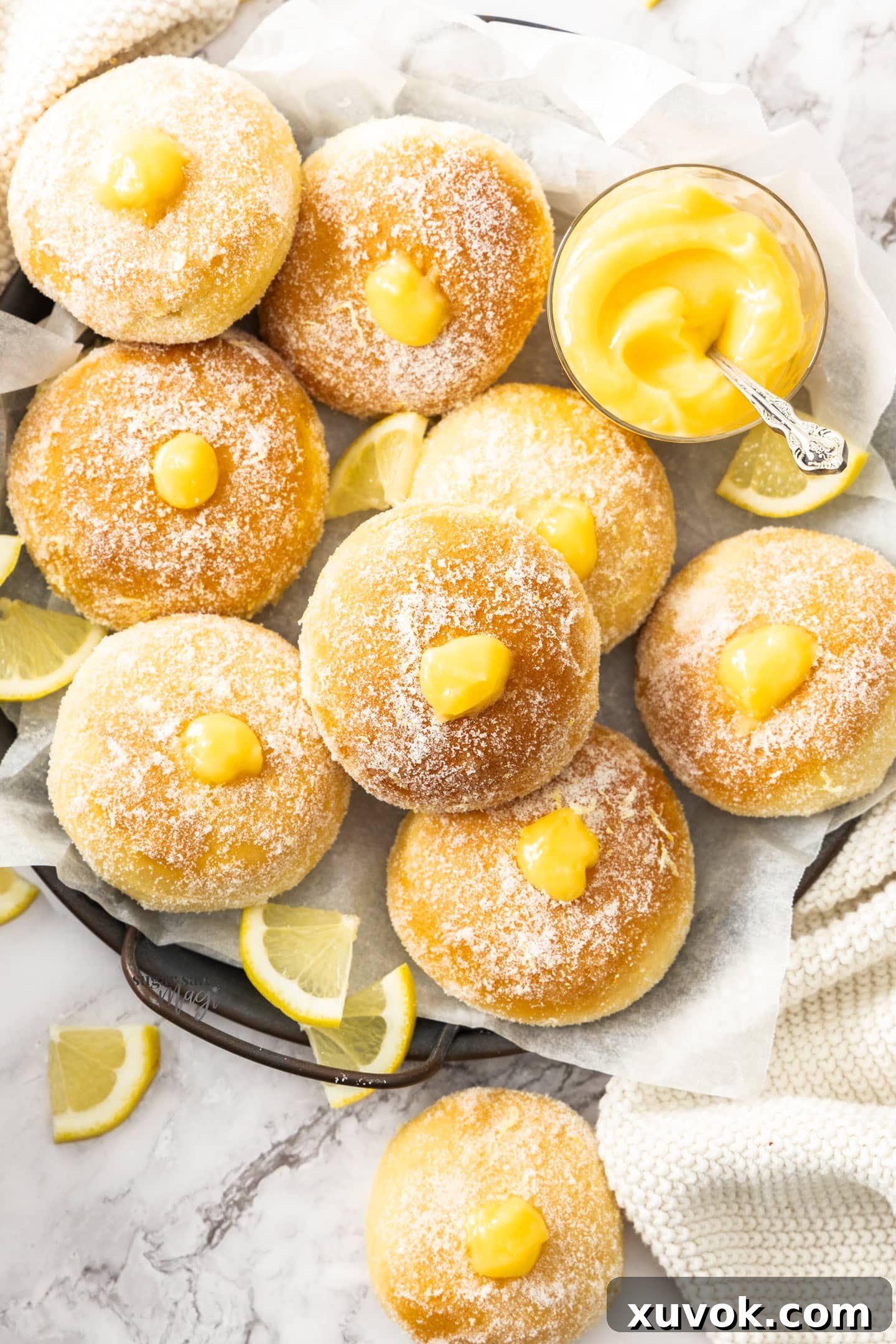 Top down view of freshly glazed lemon donuts on a metal tray.