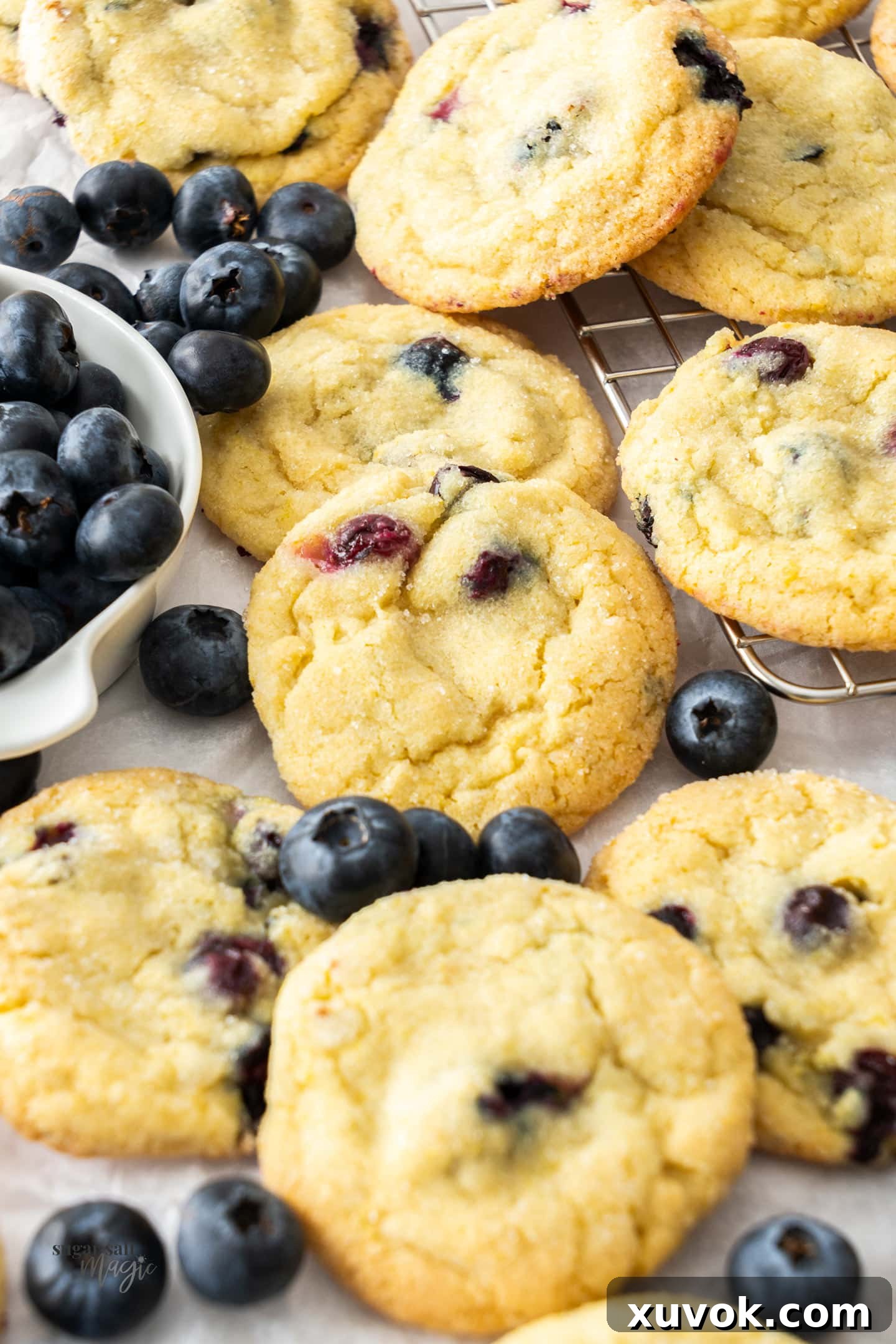 Closeup of the baked lemon blueberry cookies with fresh blueberries scattered around.