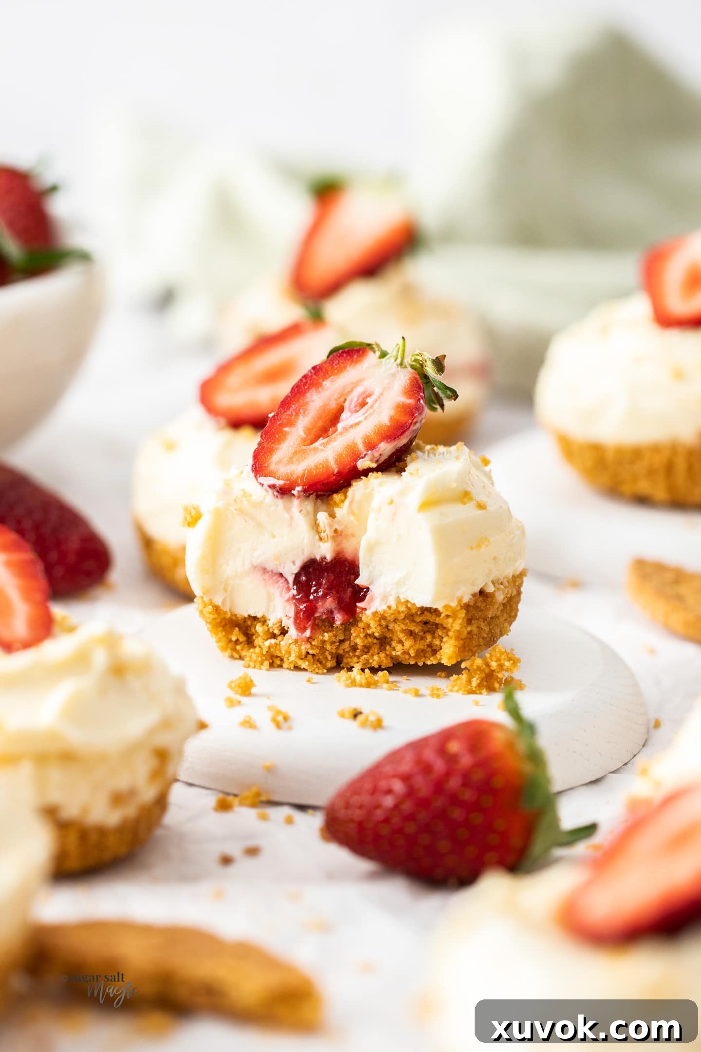 A miniature cheesecake cut open to show the strawberry filling inside.