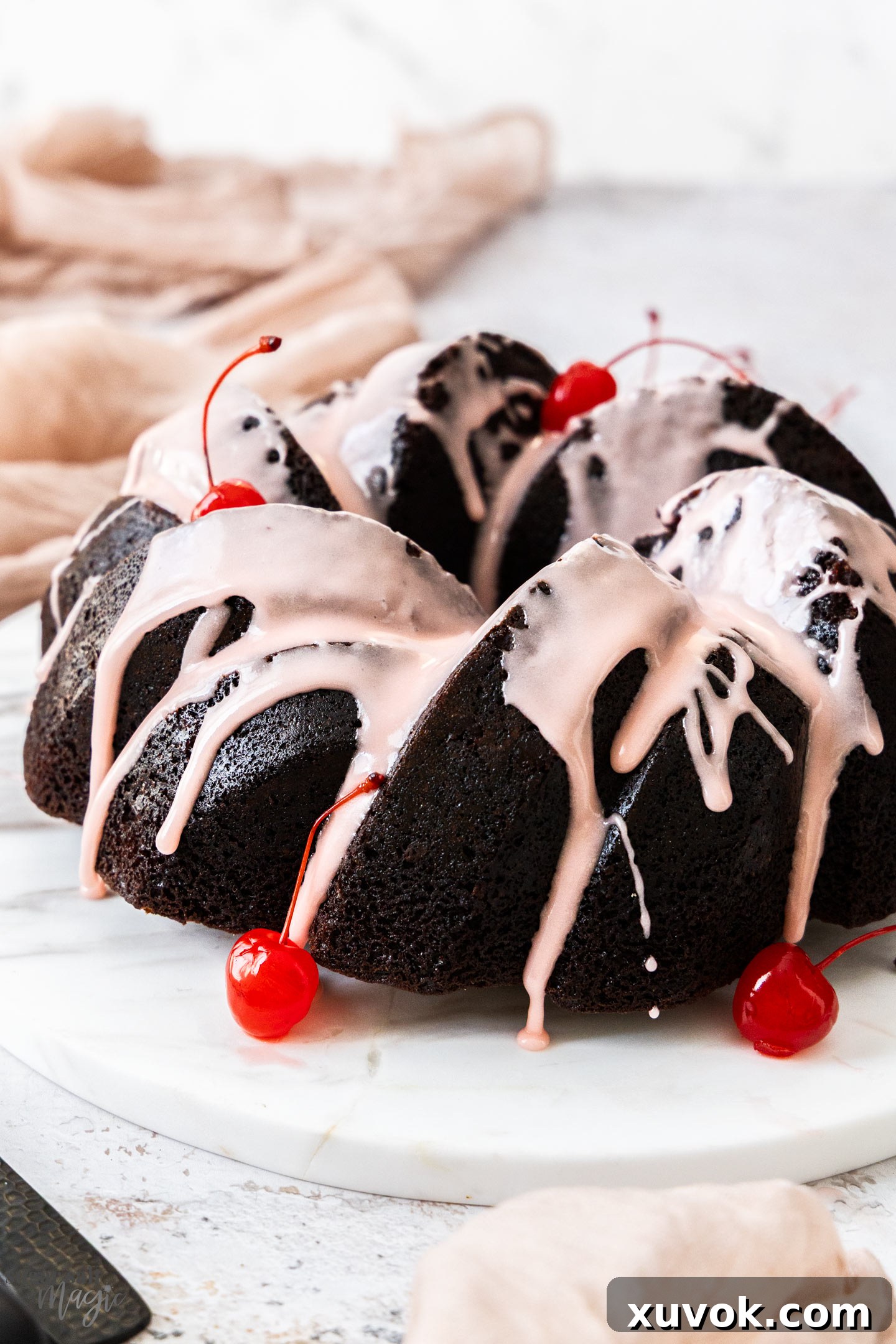 A whole chocolate cherry bundt cake on a marble platter.