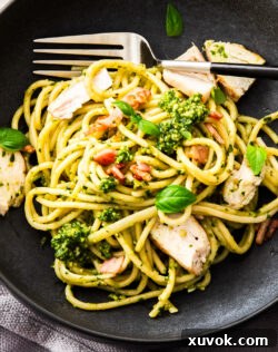 Super close up top down view of a black bowl with a serve of chicken pesto pasta.